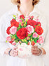 Person holding a bouquet of red and pink roses in a decorative vase.