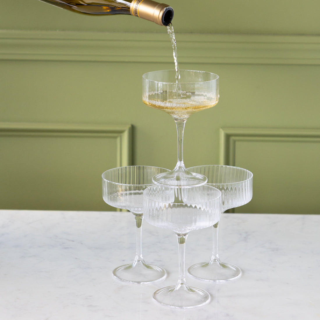 Champagne being poured into a tiered set of Fluted Textured Coupes.