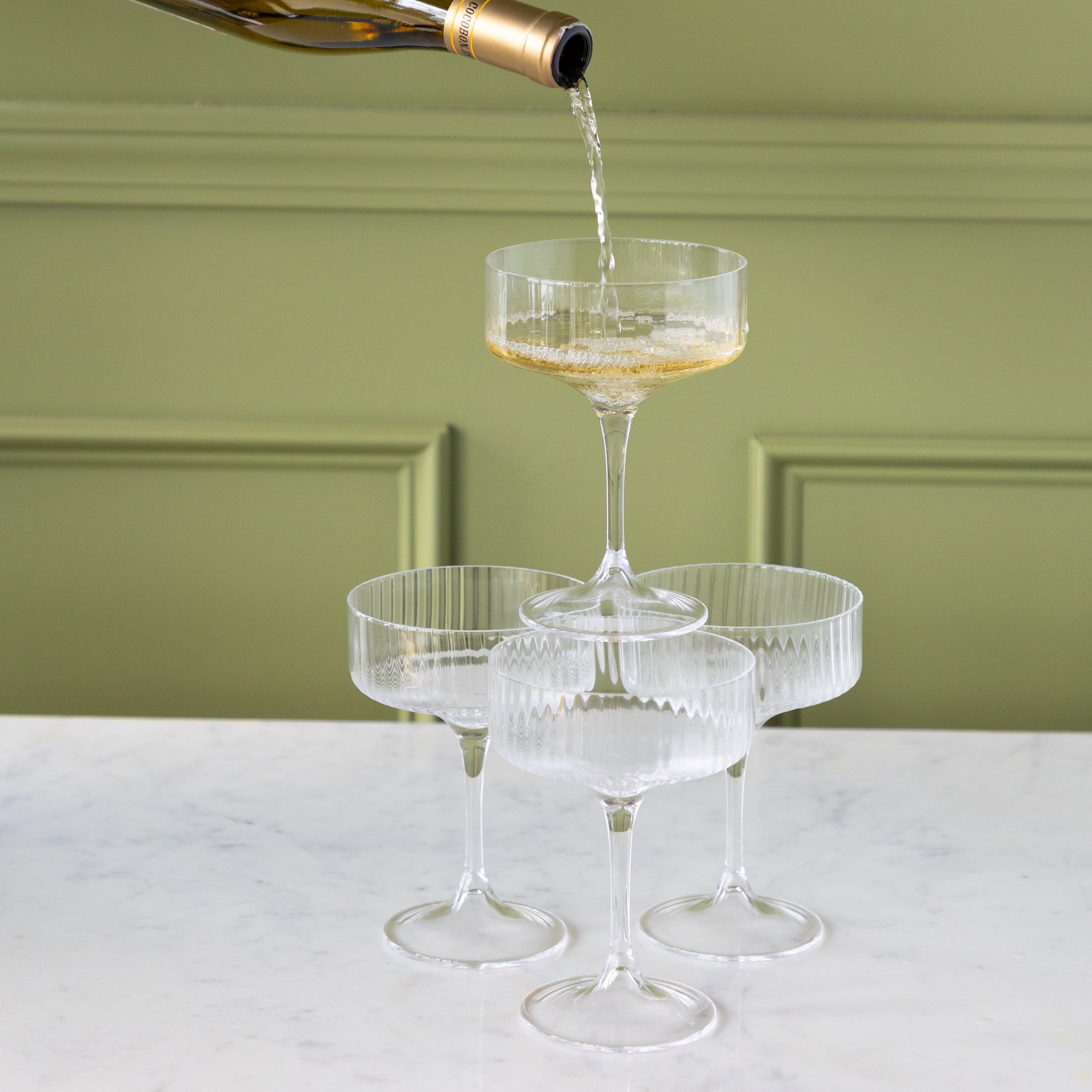 Champagne being poured into a tiered set of Fluted Textured Coupes.