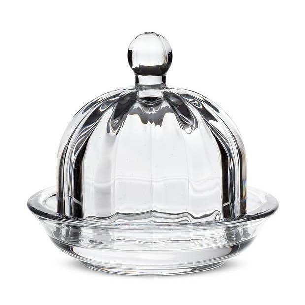 Clear glass butter dish with a lid on a white background.