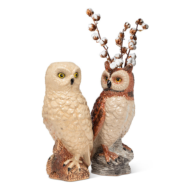 Two owl figurines with one holding a branch on a white background.