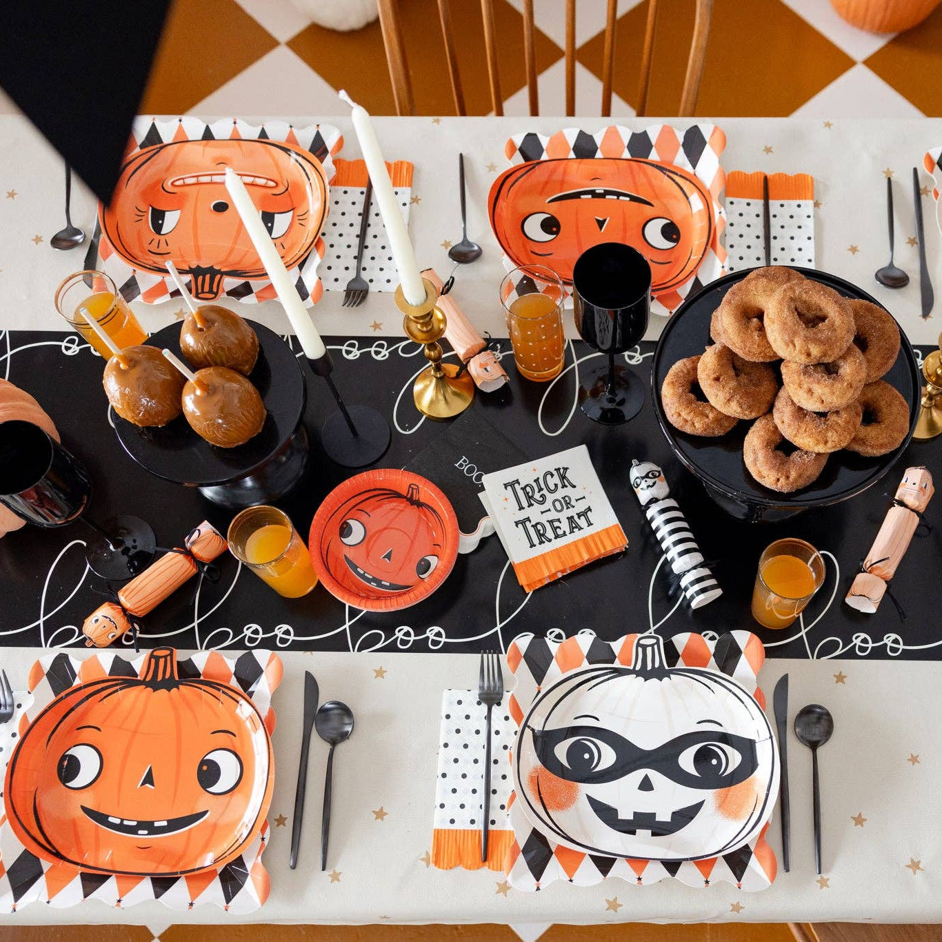 Halloween-themed table setting with decorative plates, napkins, and Pumpkin Crackers on a checkered tablecloth.