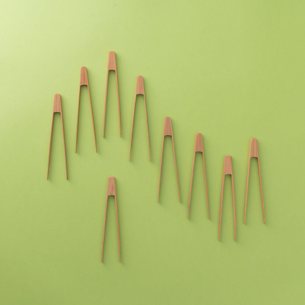 Set of wooden tongs arranged in a pattern on a green background