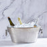 Metal ice bucket with three bottles of champagne on a marble background.