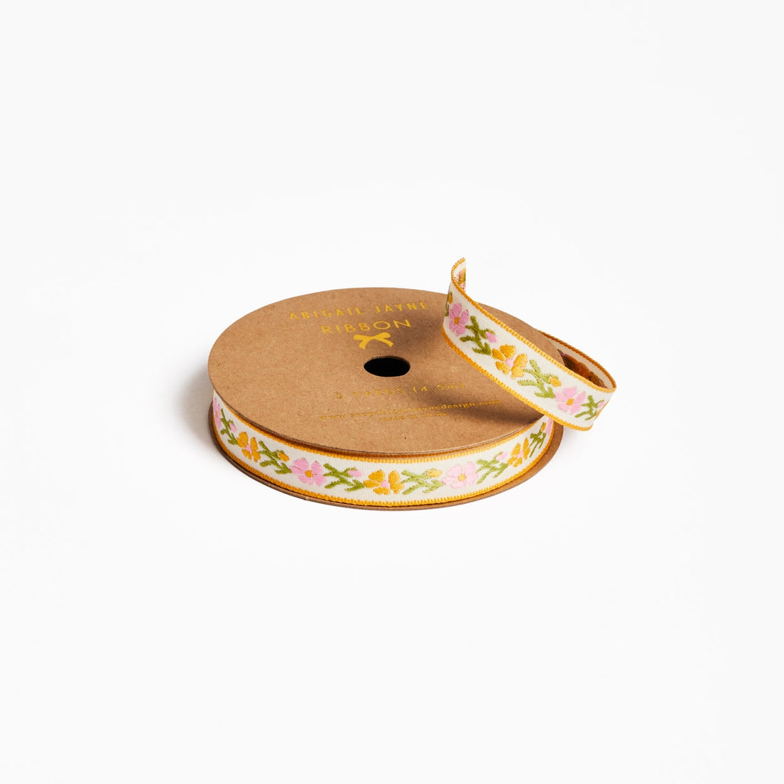 Spool of ribbon with floral design on a white background.