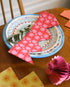 Colorful plates and napkins on a wooden table with a pink party crown laying on top. 