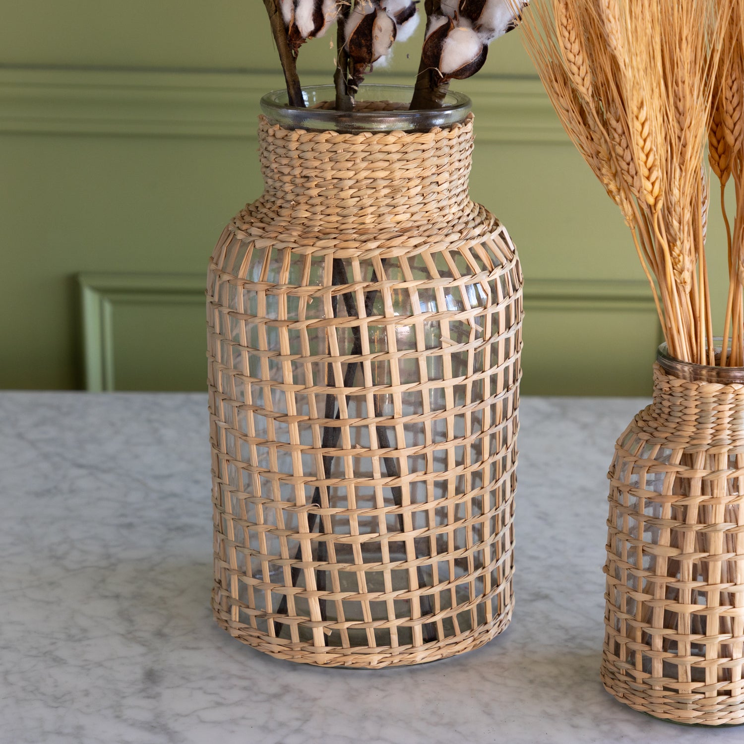 A large Rattan Wrapped Glass Vase on a marble table.