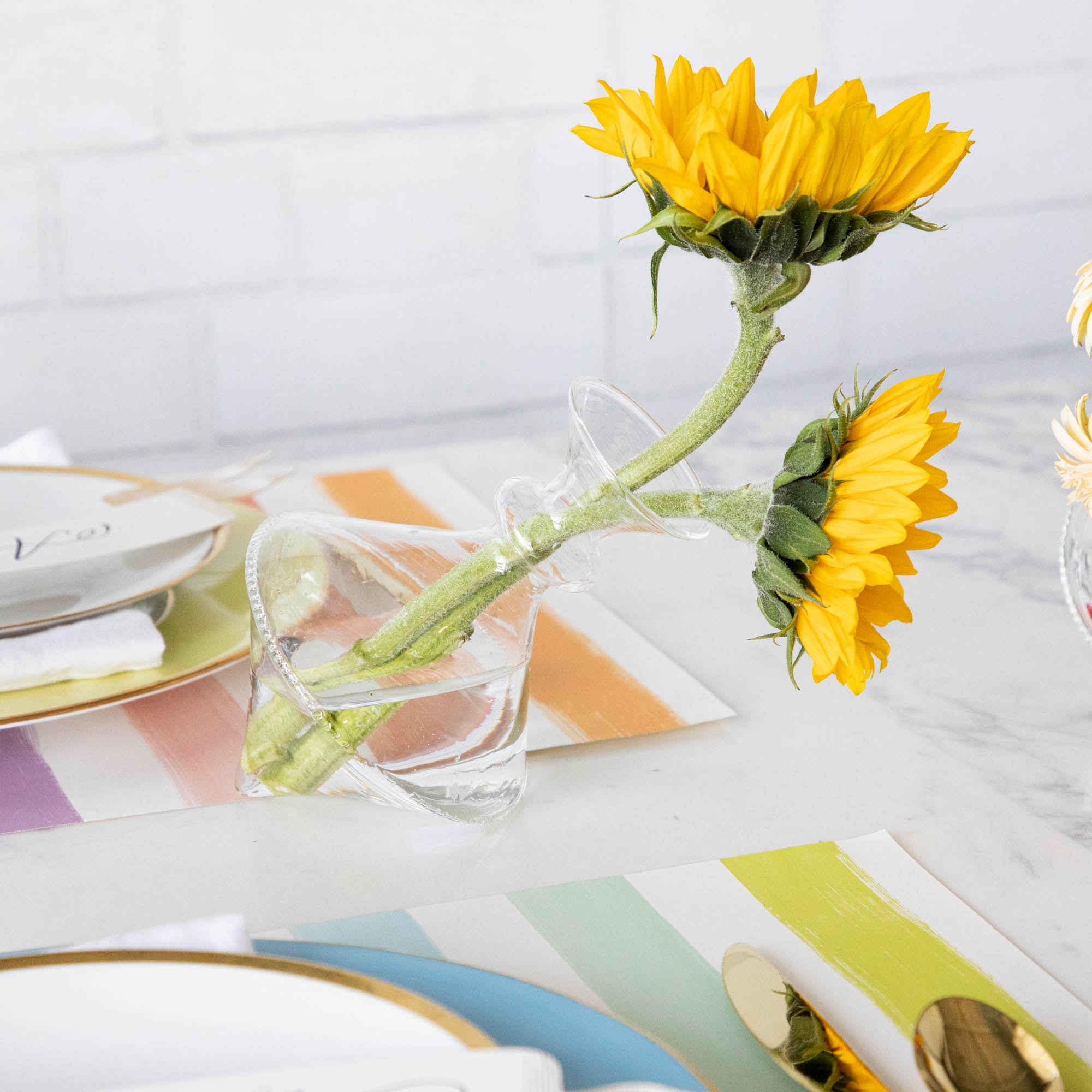 A table setting with small bouquets of sunflowers arranged in Qualia&