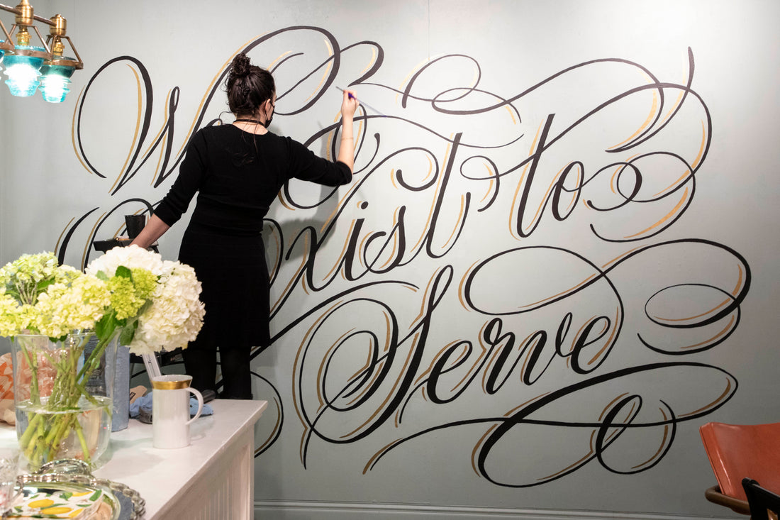 A person painting calligraphy on a wall. 
