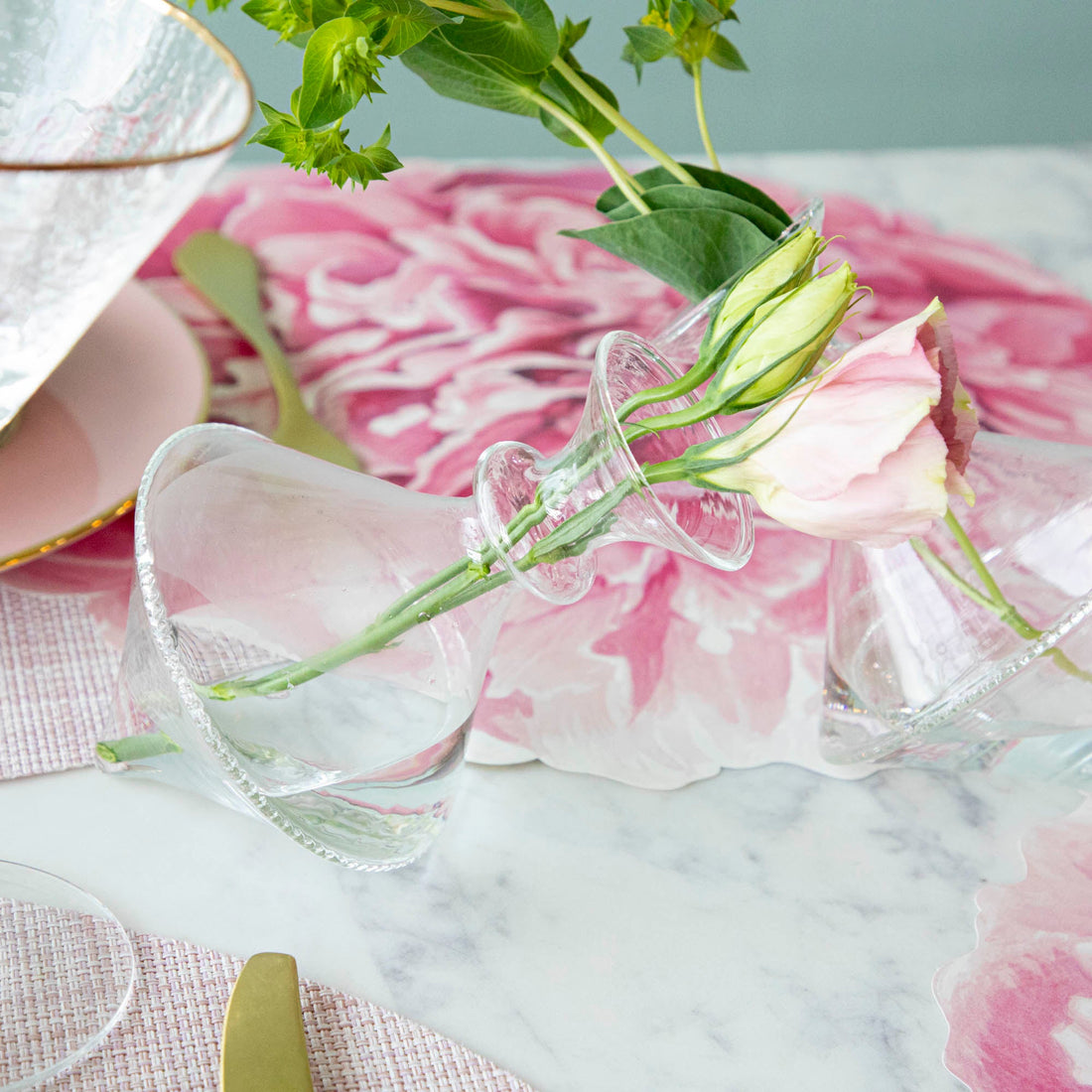 A pink and white table setting with a Qualia Mouth Blown Clear Vase - Exclusively at Hester &amp; Cook of favorite flowers.