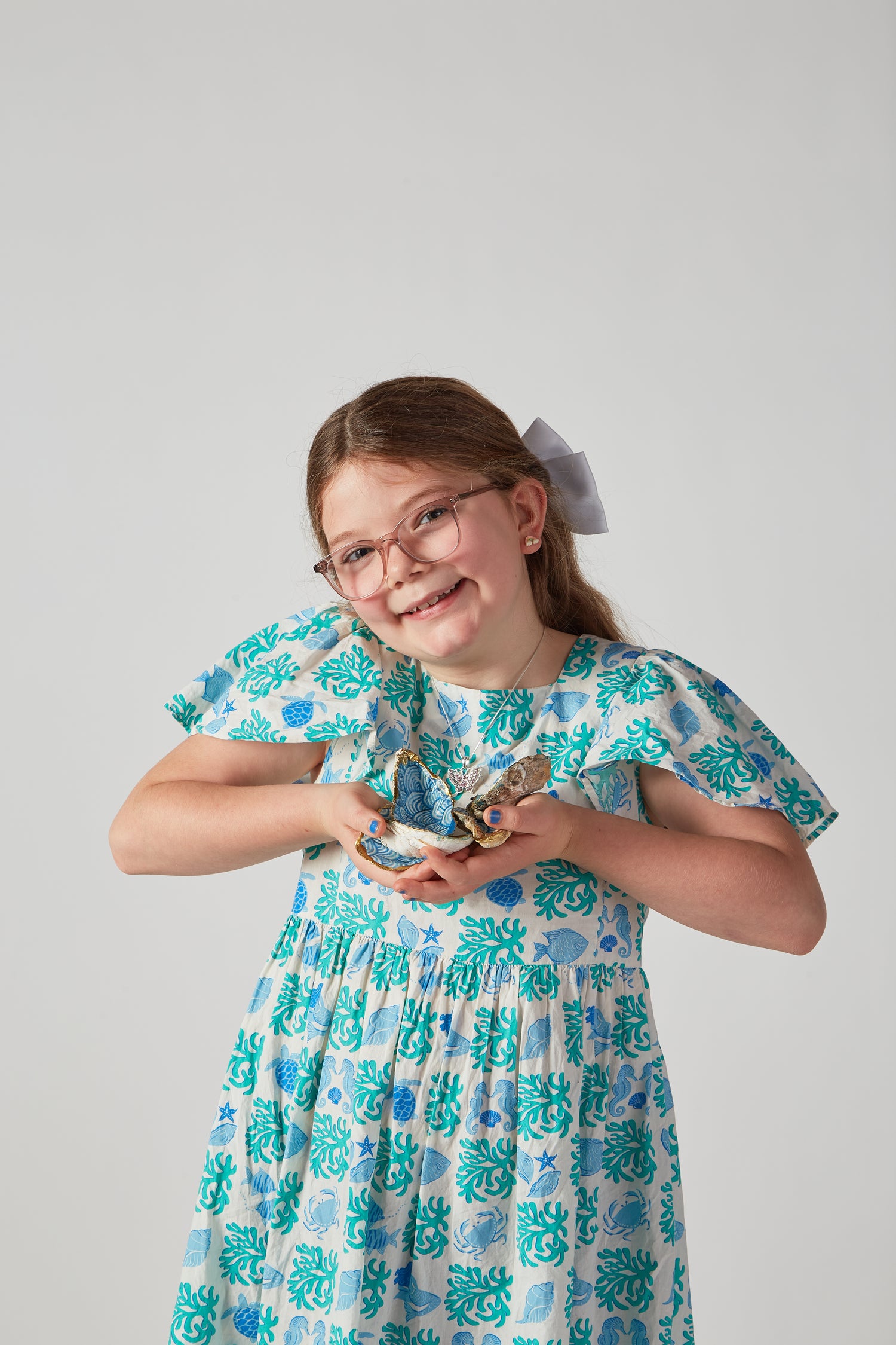 Young girl wearing a floral dress with a plain background.