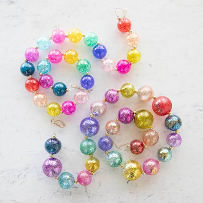 Colorful iridescent and stubble ball garland on a marble table.