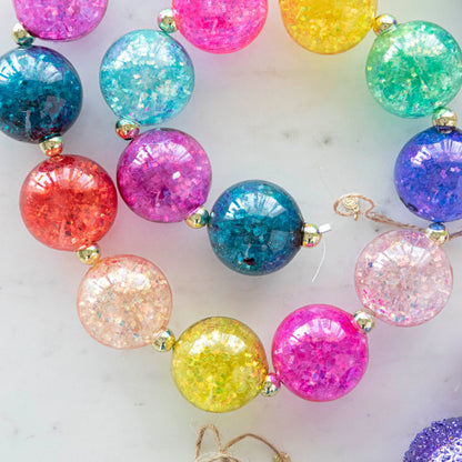 A colorful iridescent ball garland on a marble table.