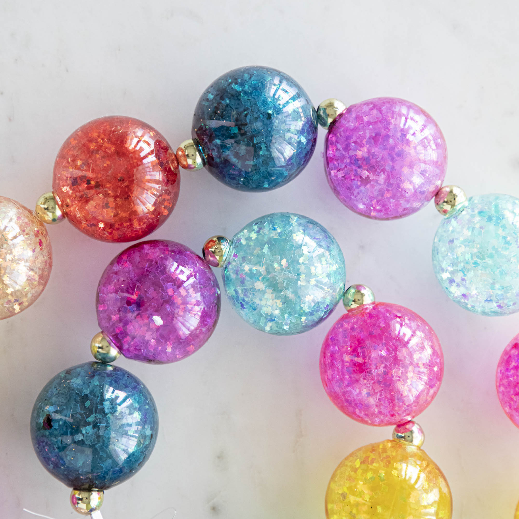 A colorful iridescent ball garland on a marble table.