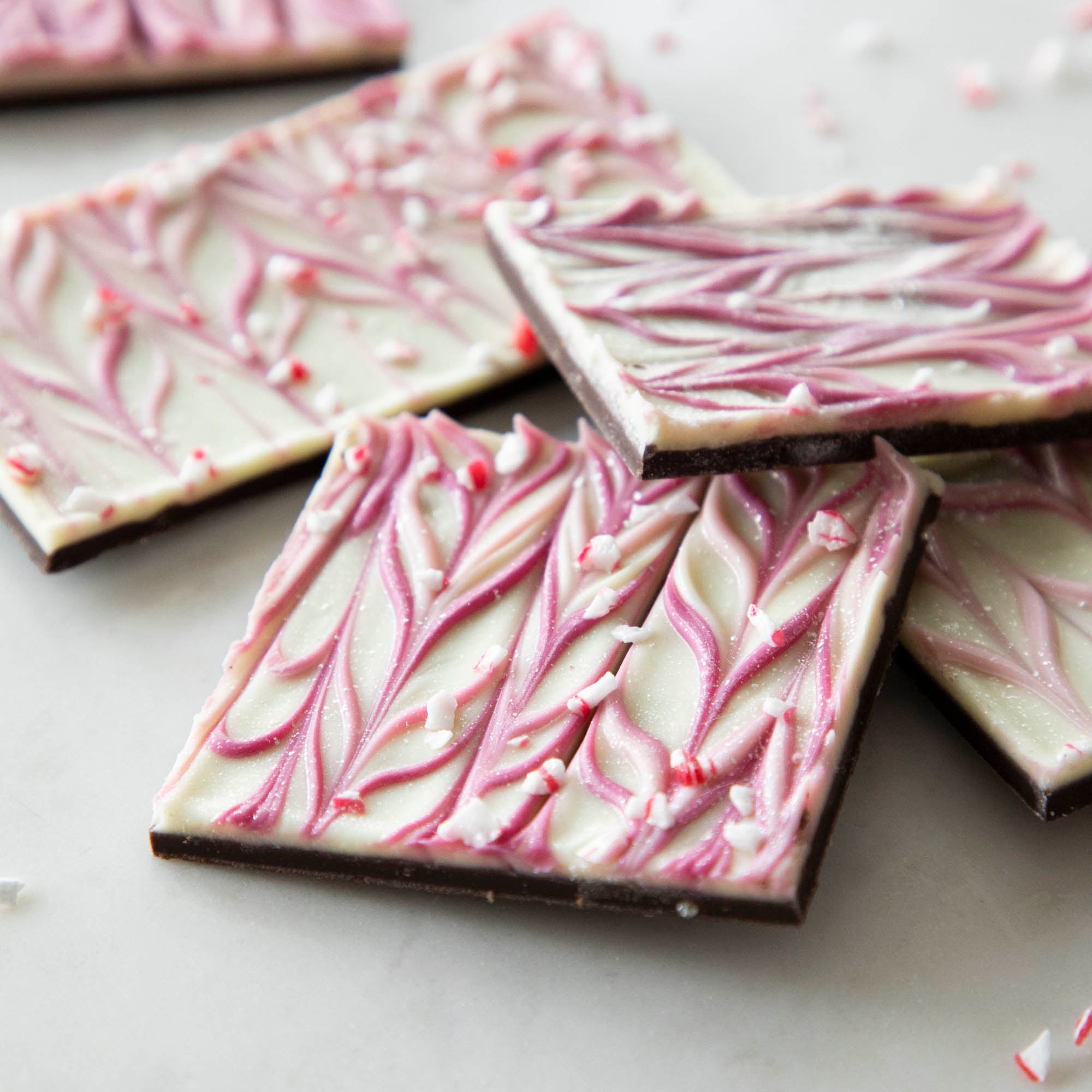 Hester &amp; Cook Sparkle Bark is a delightful chocolate treat made with all-natural ingredients, featuring peppermint chocolate squares adorned with white and pink icing.