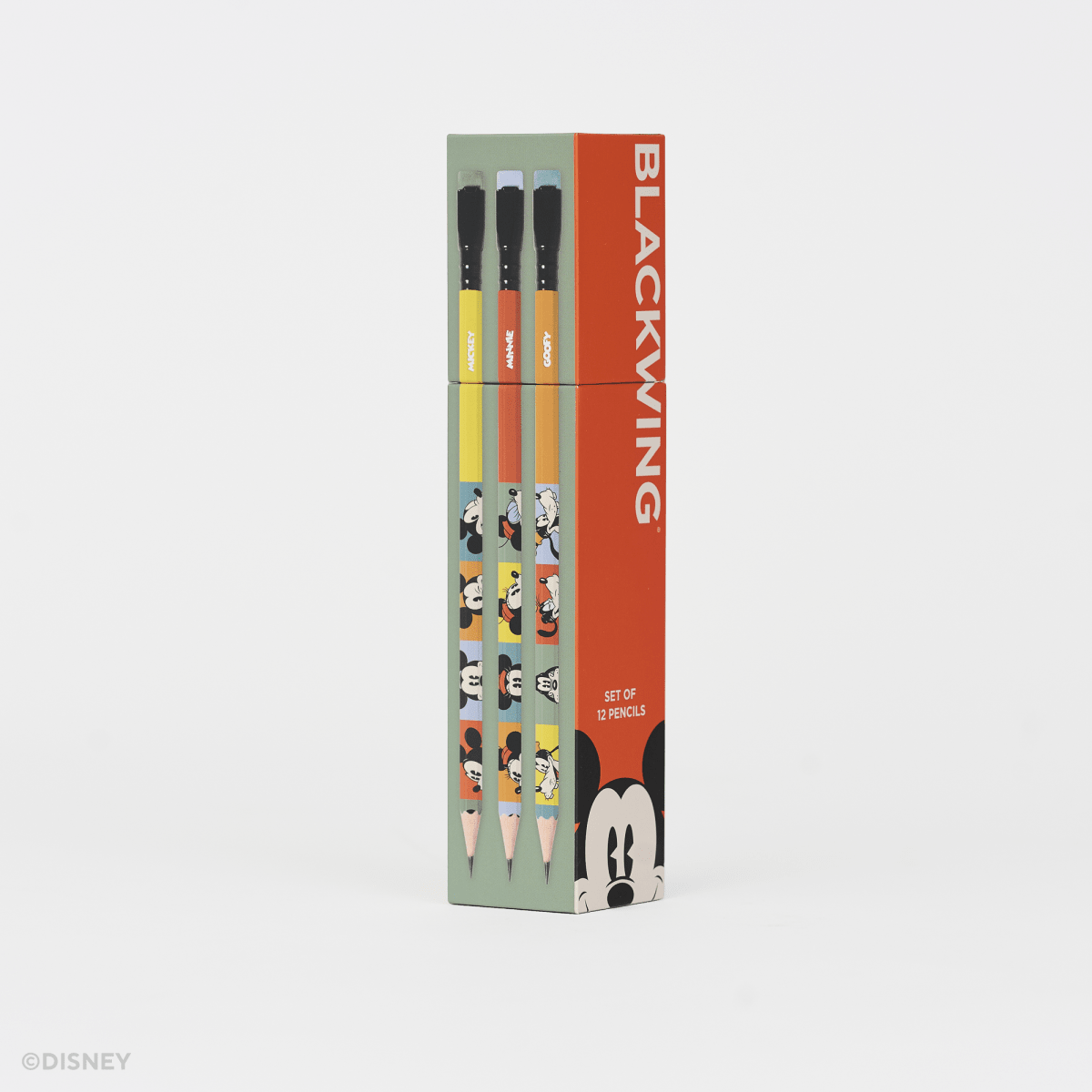 A boxed set of three Disney Blackwing pencils standing upright on a clean white background. The packaging is mint green and bright orange-red, with printed character illustrations and the word BLACKWING prominently visible.