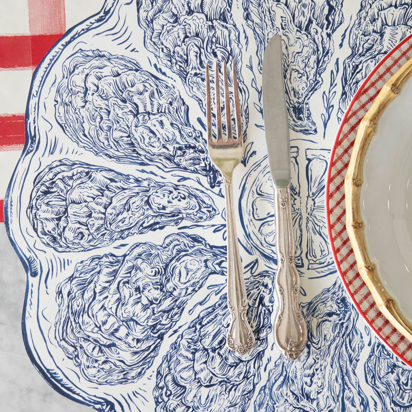 A close up of the Die-cut Blue Oyster Plate Placemat with silverware on top.