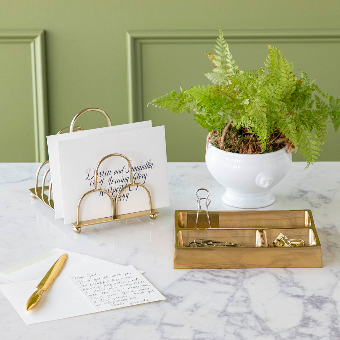 brass letter opener on desk styled with various desktop accessories 