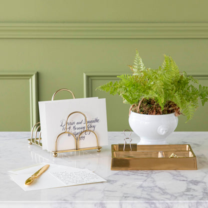 brass catchall styled on a desk with various desktop accessories