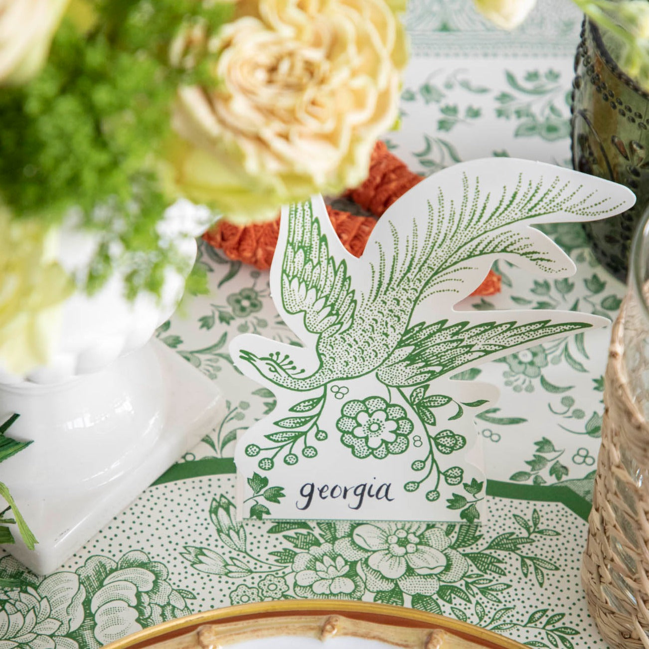 A Hester &amp; Cook Green Asiatic Pheasants Place Card and white table setting with place cards and flowers, ensuring guests feel welcomed and organized with the use of place cards.