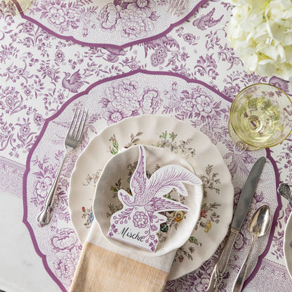 A beautiful purple and white tablescape adorned with stunning Hester &amp; Cook Die-cut Lilac Asiatic Pheasants Placemats and elegant silverware.