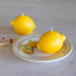 Two lemon-shaped candles on a decorative plate with a marble background.