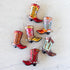 Colorful cowboy boot ornaments on a marble table.