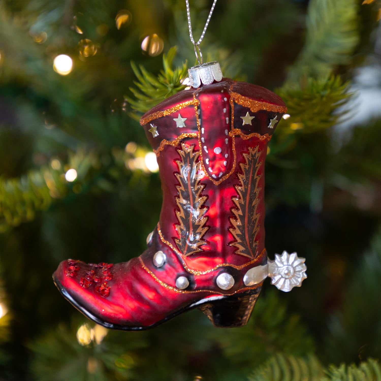 Red cowboy boot ornament on a Christmas tree.
