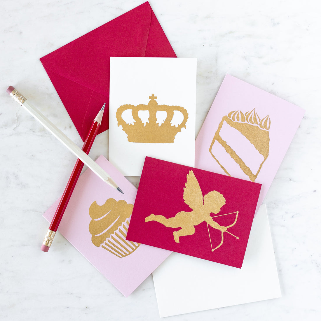 Catherine Greenup cards arranged on a table with two pencils crisscrossed atop.