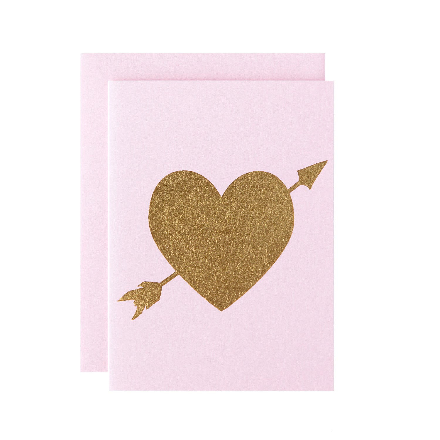 A gold foiled heart with an arrow going through it on a light pink card with a matching envelope.