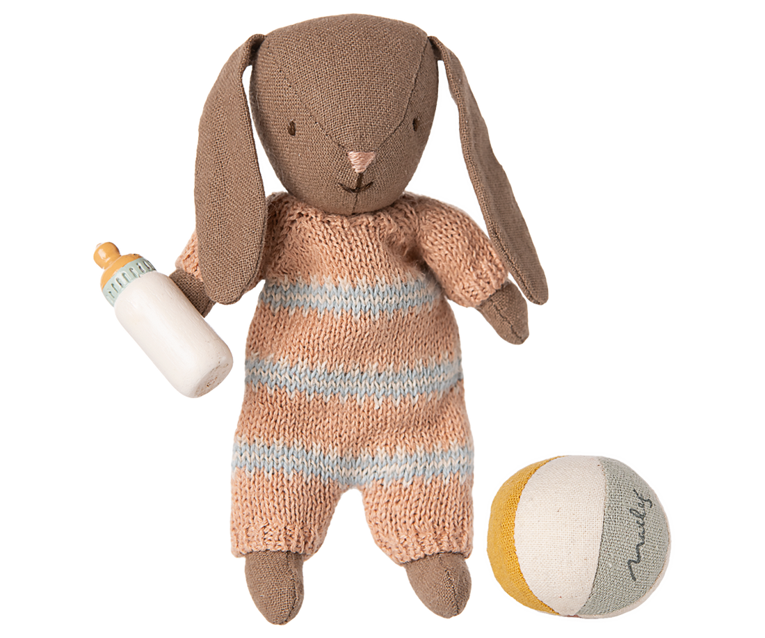 Knitted toy rabbit in a striped outfit with a bottle and ball on a white background.