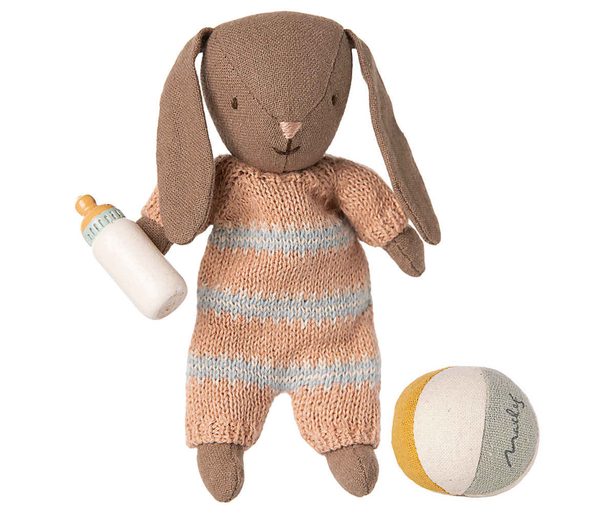 Knitted toy rabbit in a striped outfit with a bottle and ball on a white background.