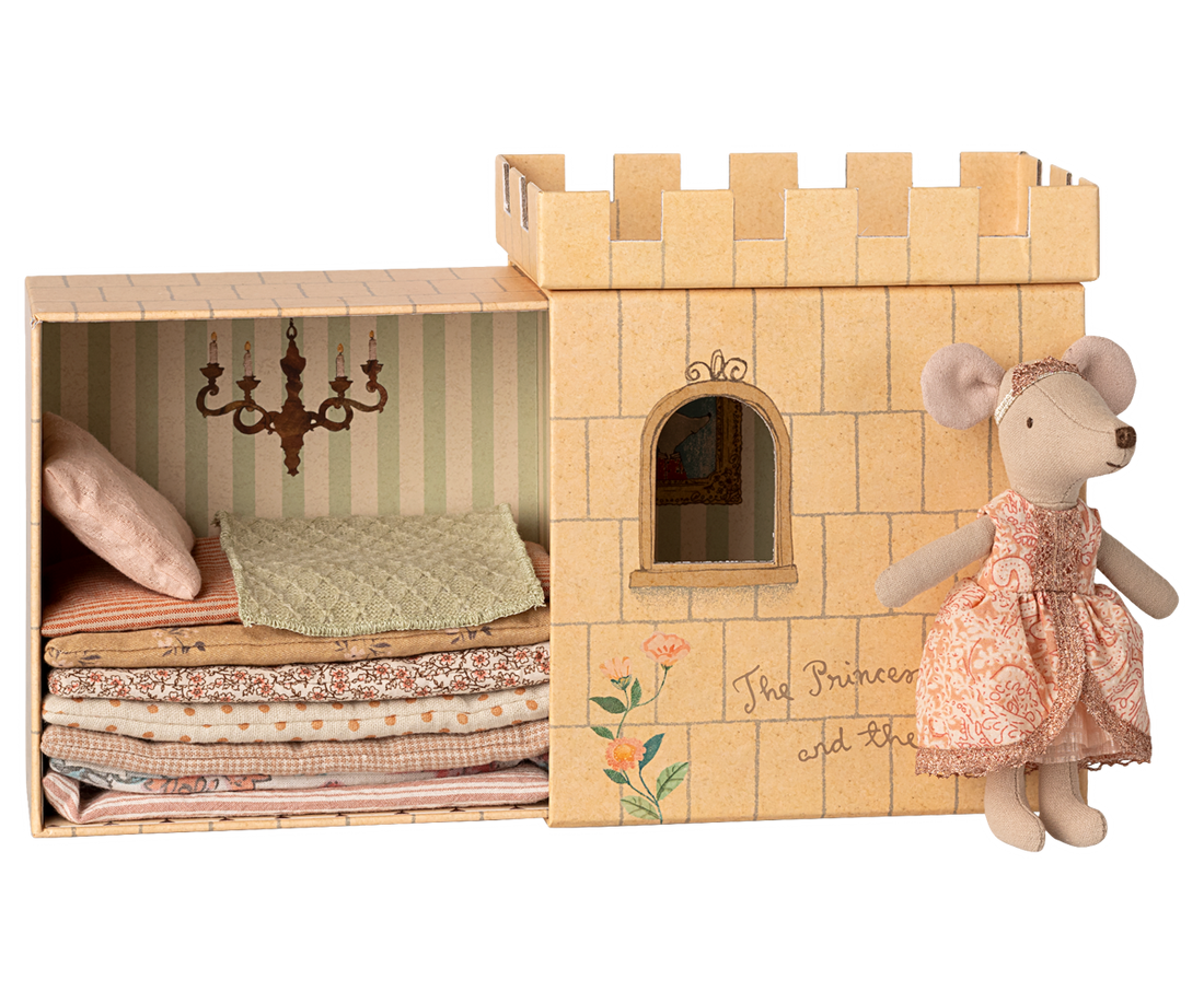 Castle toy with bedding and a mouse doll in a dress on a white background.