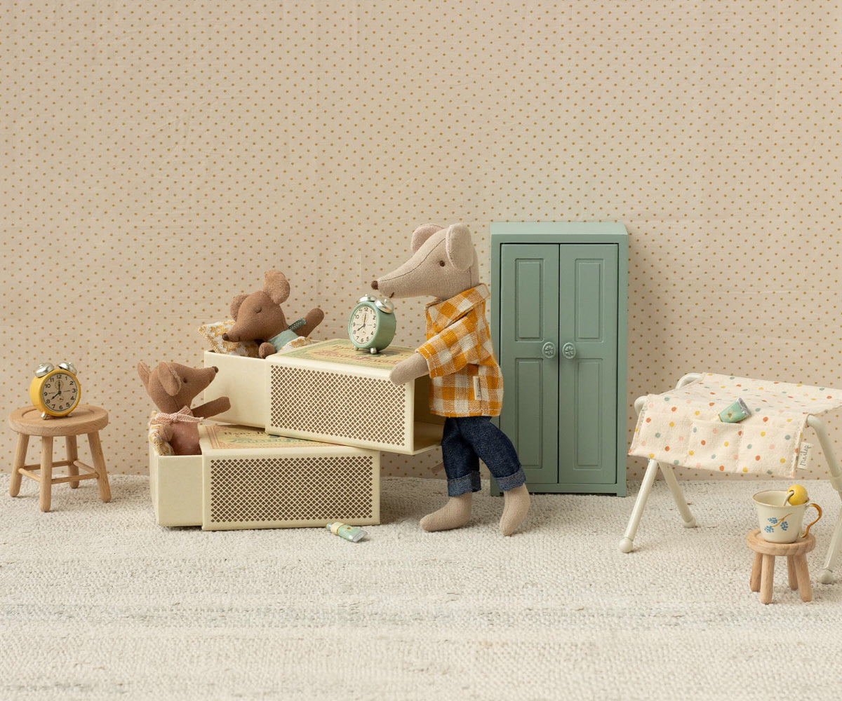 Miniature scene with toy animals in a room setting on a beige textured background.