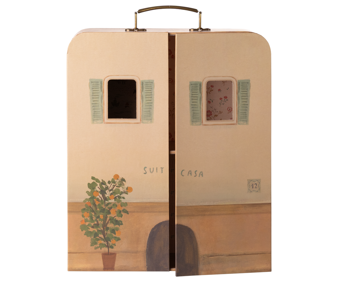 Cardboard box designed to resemble a house with windows and a plant, featuring the brand &