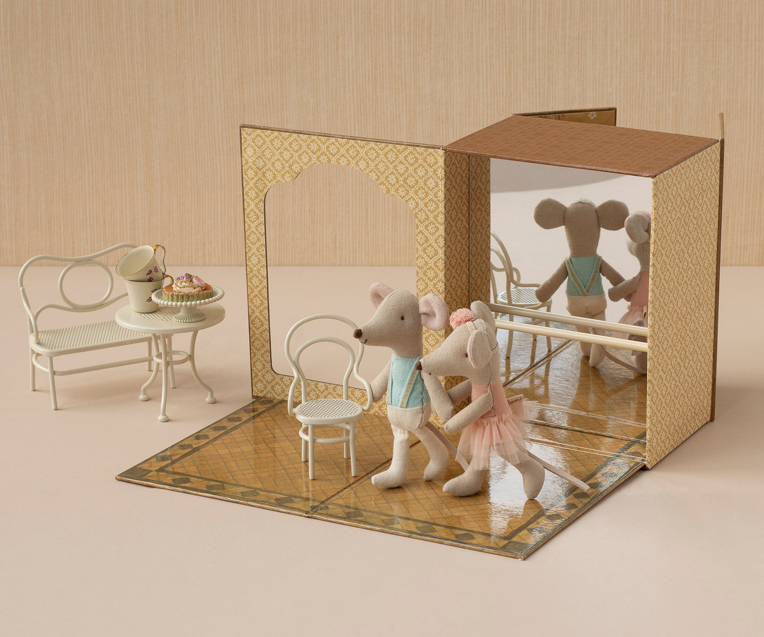 Toy mouse figures in a decorative box with a miniature table and chairs.