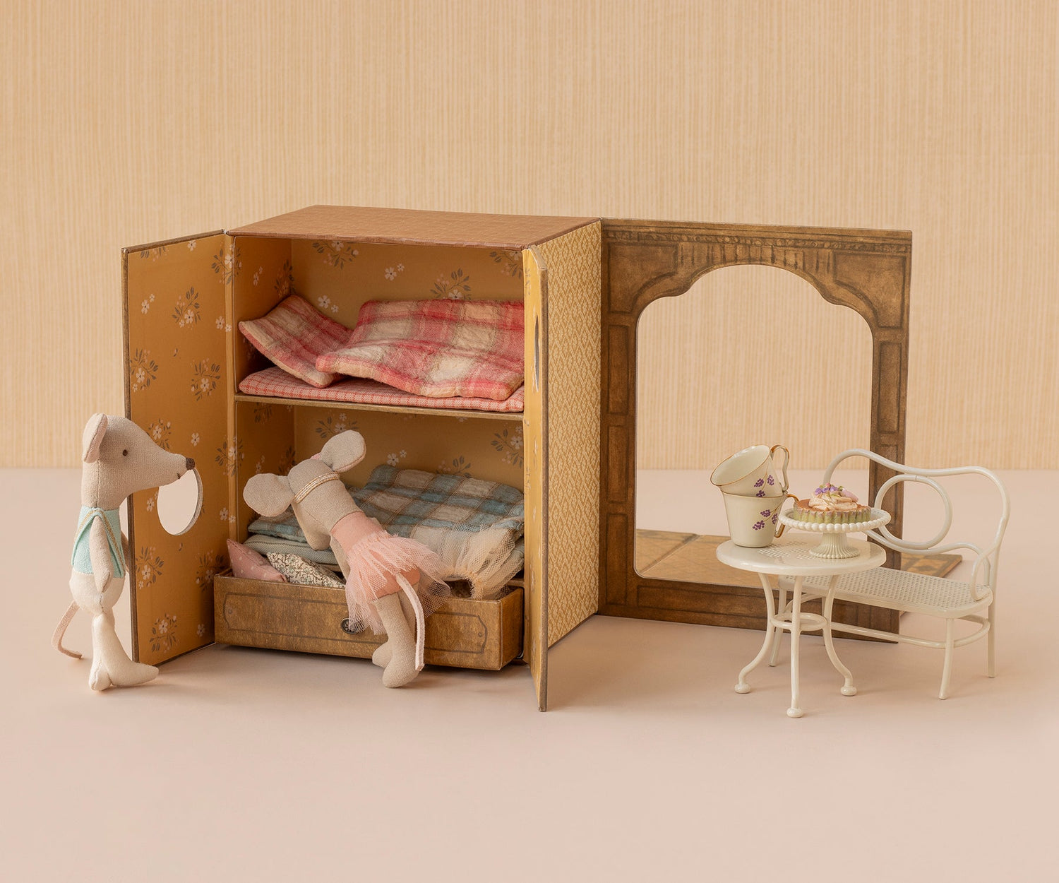 Miniature dollhouse with furniture and toys on a neutral background.
