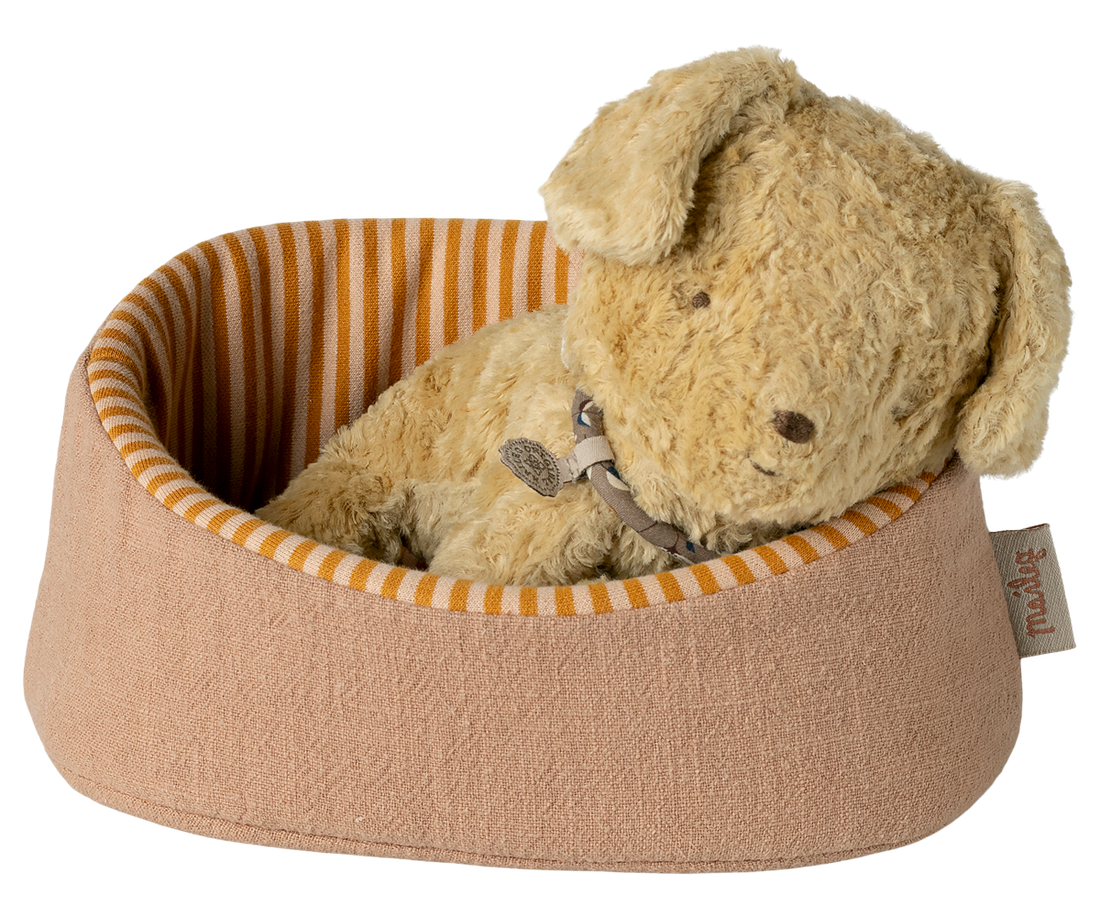 Plush dog toy in a brown pet bed with orange stripes on a white background