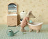 Toy mouse in a bathtub with bathroom furniture and decor in the background.