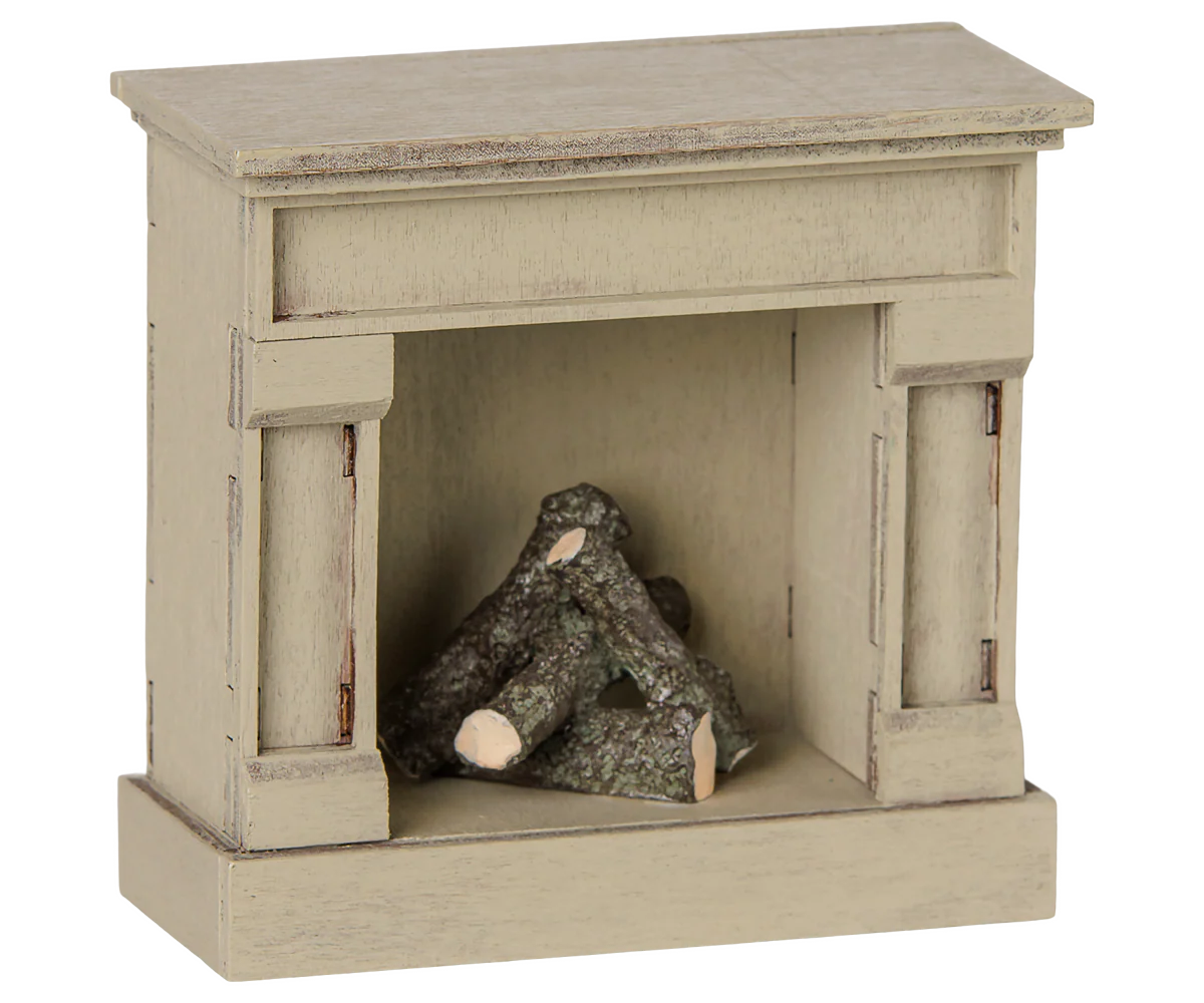 A miniature fireplace mantel figurine in a distressed beige finish, featuring a small stack of faux logs inside the fireplace opening, shown against a plain white background.