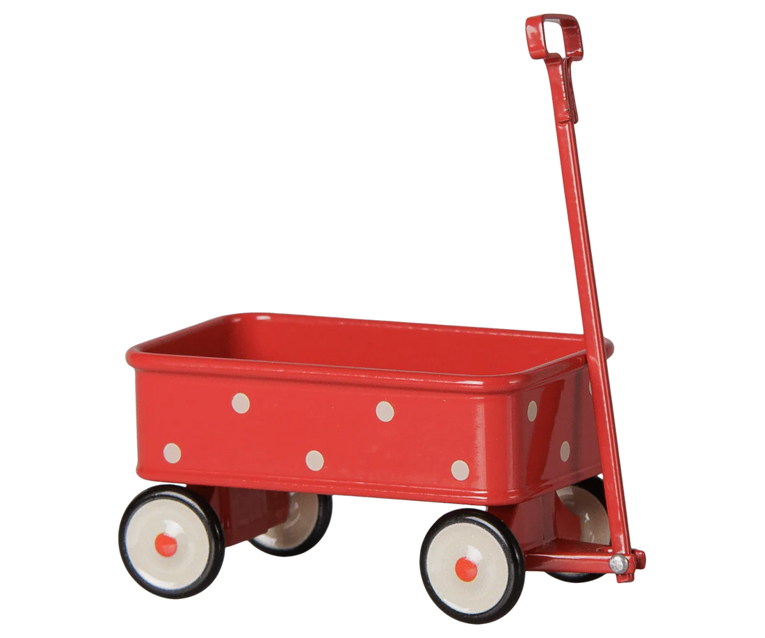 A classic red metal toy wagon with white polka dots, cream-colored wheels with black trim, and a red D-handle, shown against a plain white background.