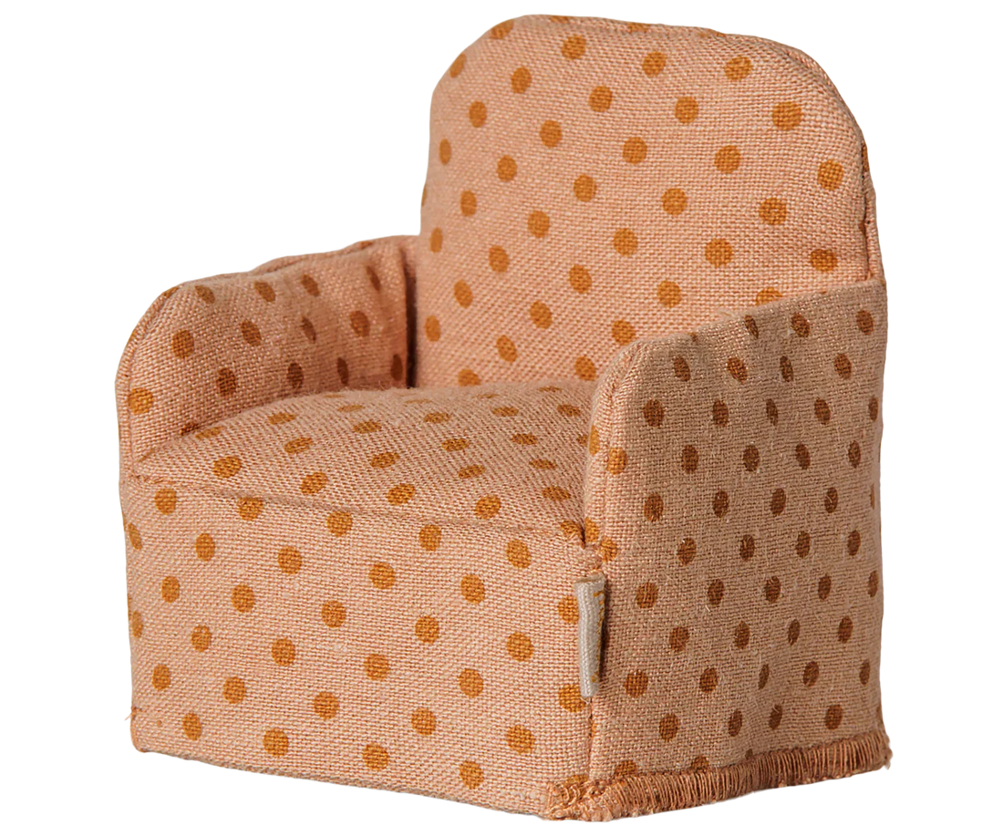A small upholstered armchair with a warm peach fabric and brown polka dots, shown on a plain white background.