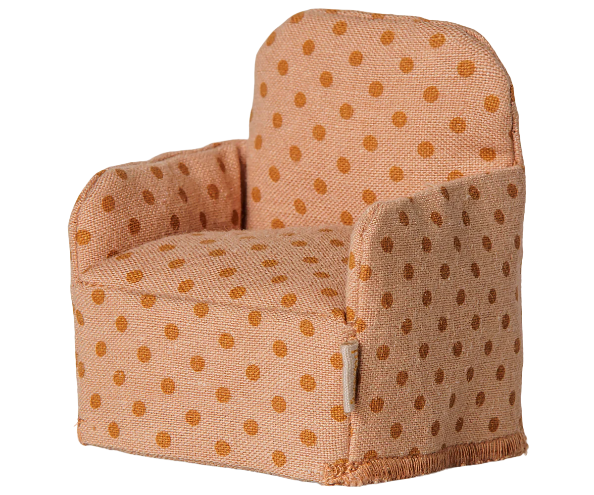 A small upholstered armchair with a warm peach fabric and brown polka dots, shown on a plain white background.