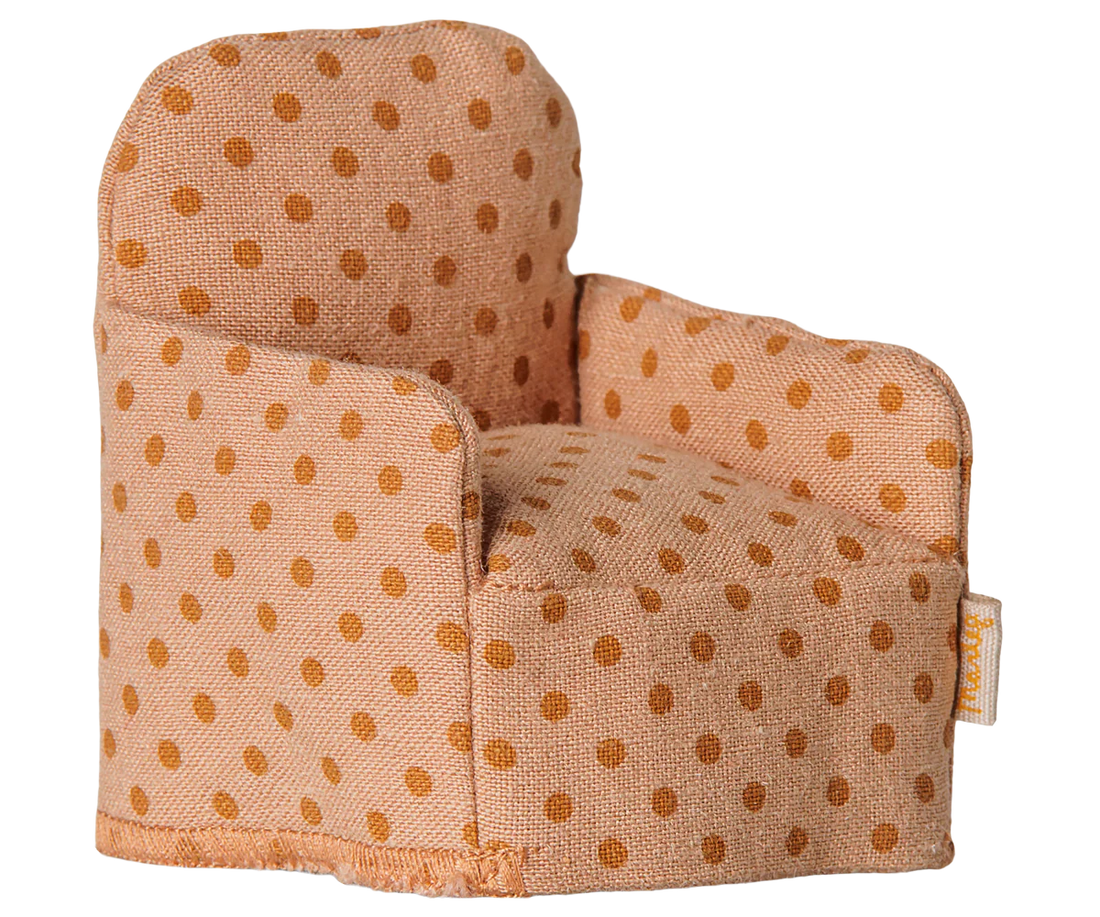 A small fabric armchair with a warm beige base and brown polka dots, photographed on a plain white background. A small fabric brand tag is visible on the right side.