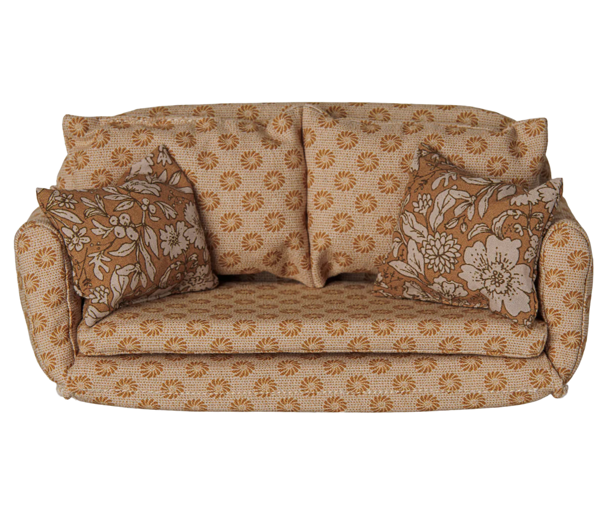 A vintage-style two-seater miniature sofa with rolled arms upholstered in a beige fabric with a brown sunflower pattern, featuring two matching floral throw pillows.