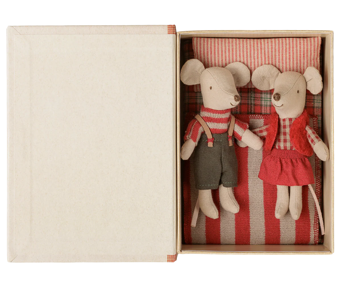 A pair of vintage-style paper mouse dolls in a cream-colored gift box. The left mouse wears a red-and-white striped sweater and dark gray trousers, while the right mouse wears a red vest over a red-and-white checkered shirt and a red dress.