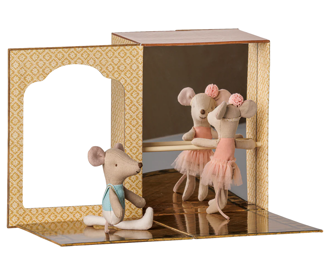 A miniature ballet scene display featuring three small plush mouse ballerina figures. One mouse sits on the floor wearing a light blue bow tie, while another mouse in a pink tutu dances in front of a mirrored backdrop inside a patterned wooden box.