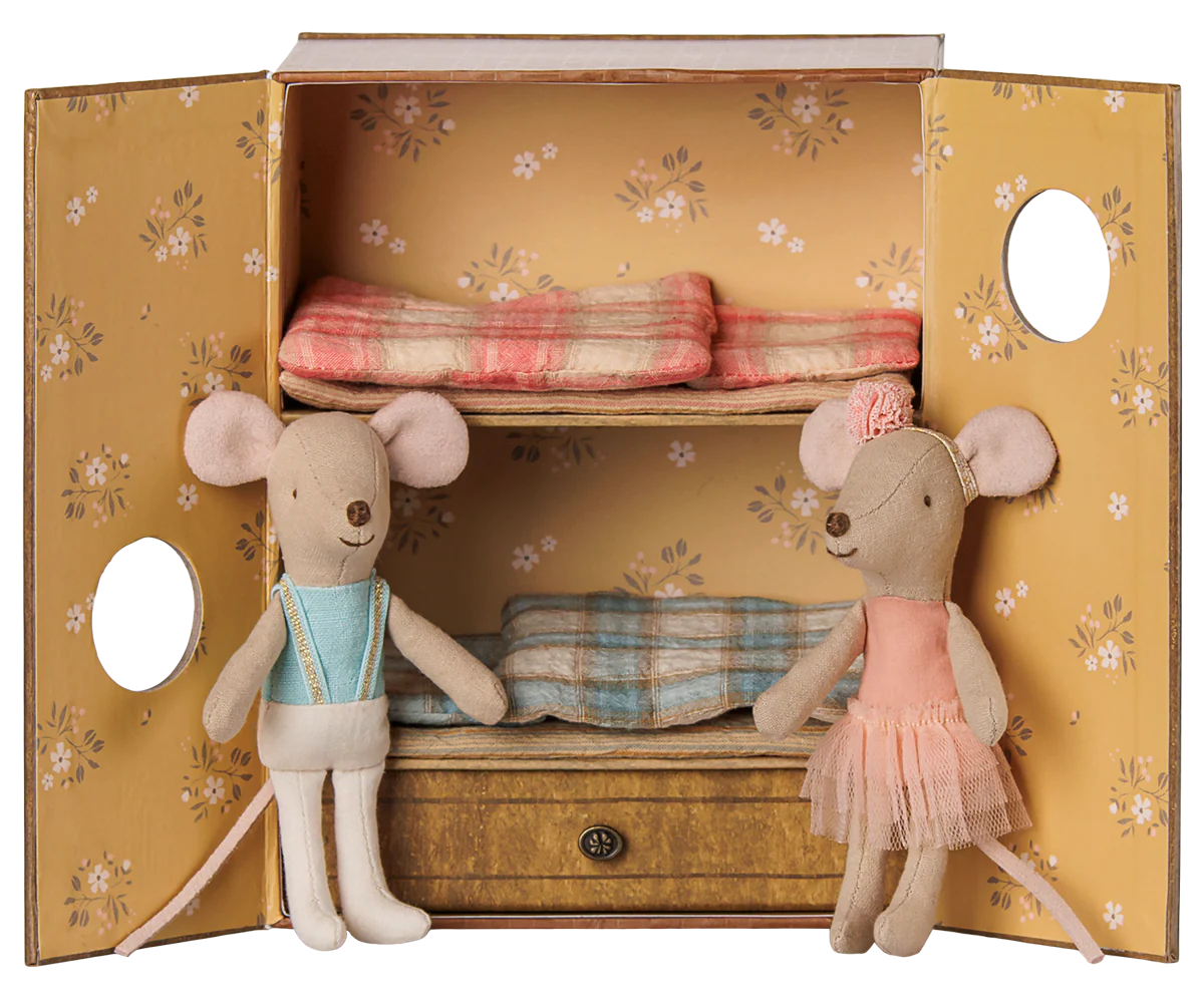 A miniature dollhouse wardrobe with floral yellow doors, two shelves, and a drawer, styled with two plush mouse dolls dressed in pastel clothing.