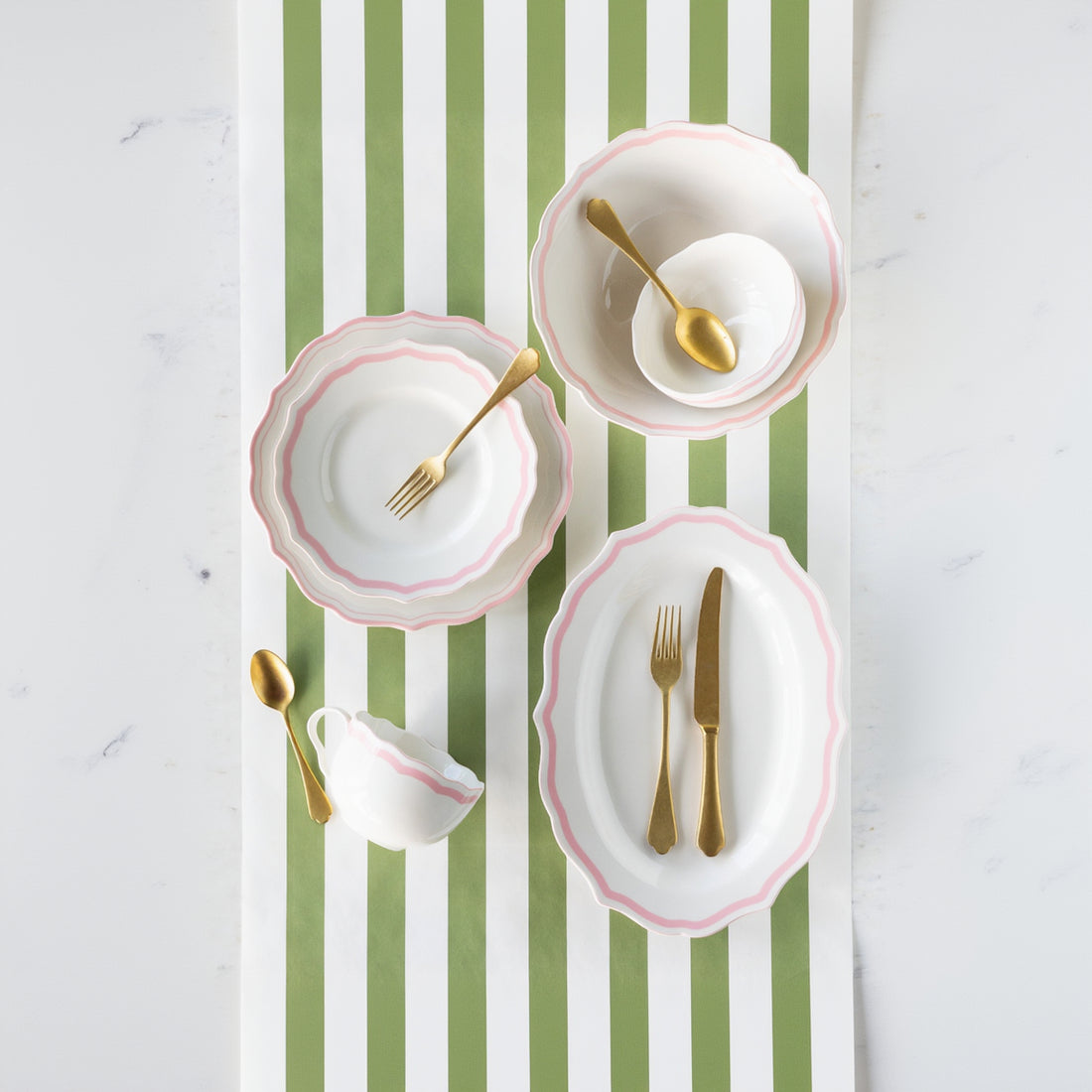 Set of white plates with pink rims and gold cutlery on the Moss Classic Stripe Runner.