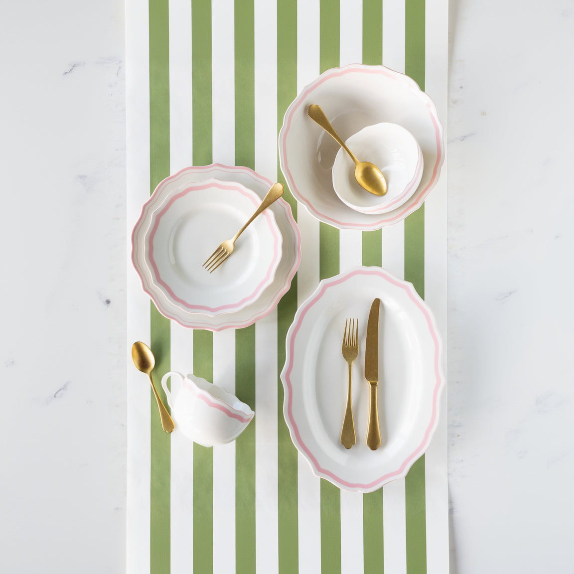Set of white plates with pink rims and gold cutlery on the Moss Classic Stripe Runner.